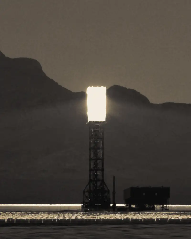 A solar power tower glowing above a field of mirrors in the desert